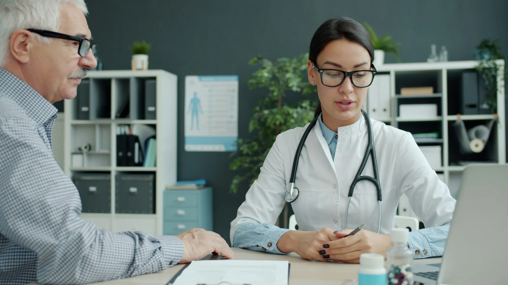 Una médica conversa con un paciente mayor en su consulta