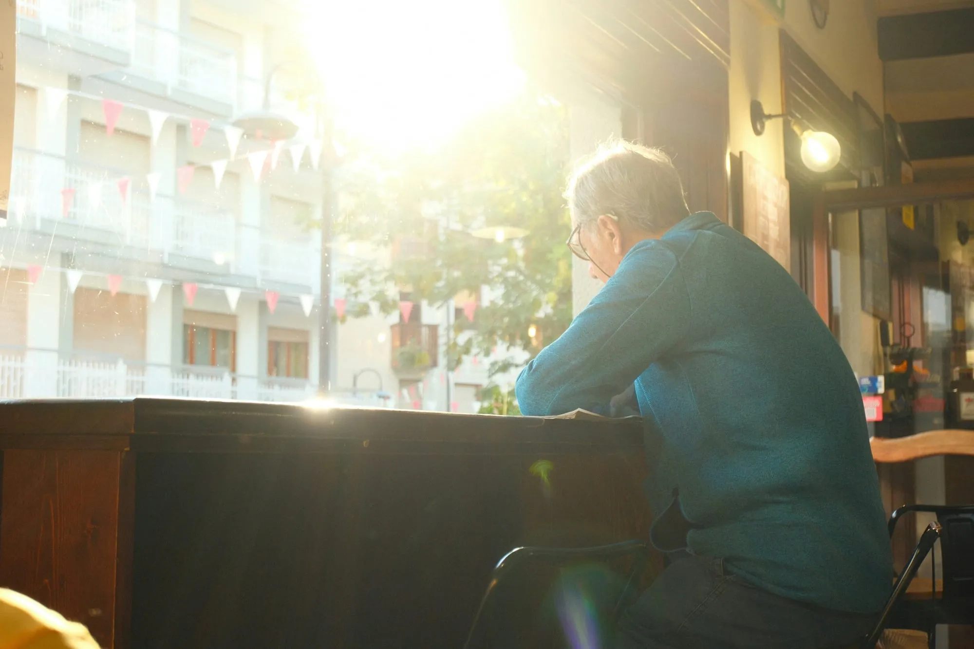 Un hombre en un café, junto a una ventana bañada por el sol