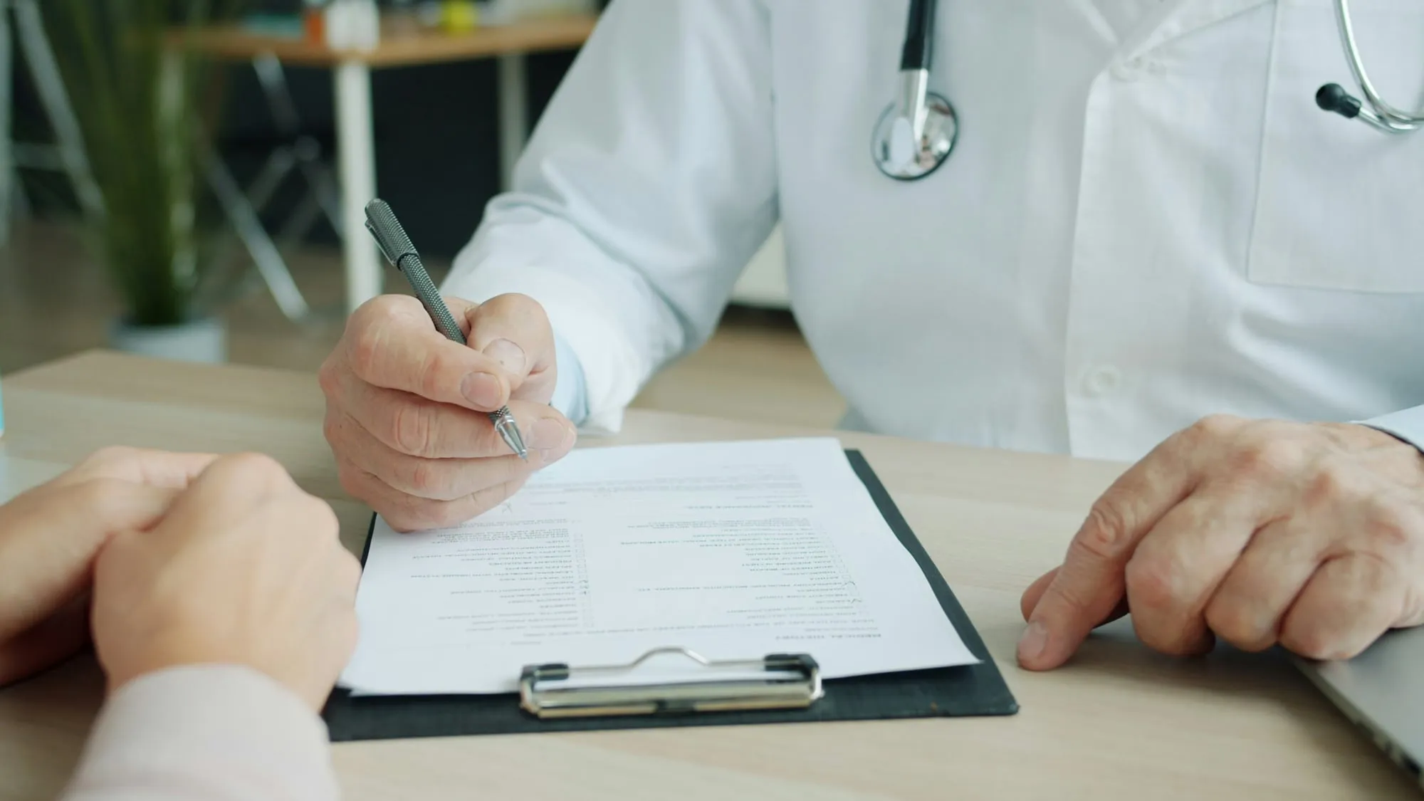 Manos de un médico anotando en una historia clínica