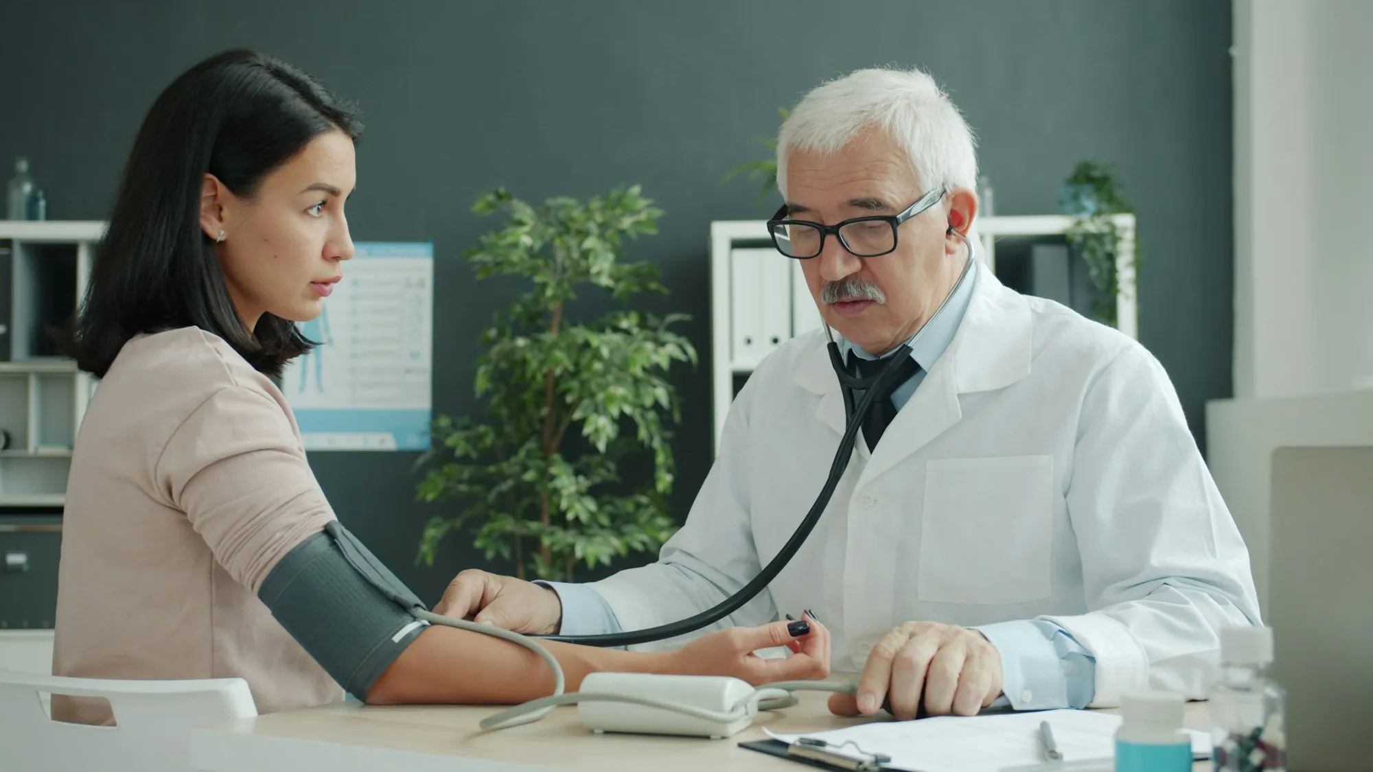 Un médico toma la tensión a una paciente en la consulta